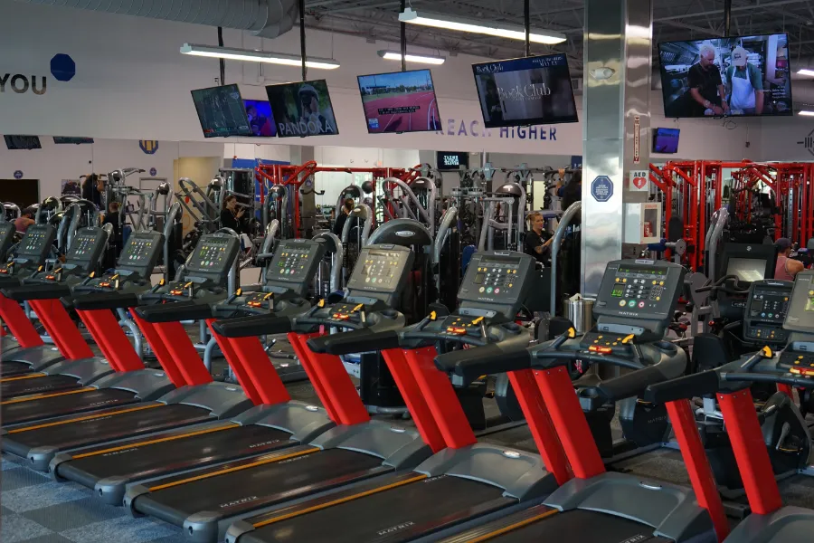 treadmills in a gym with TV's in front of them.