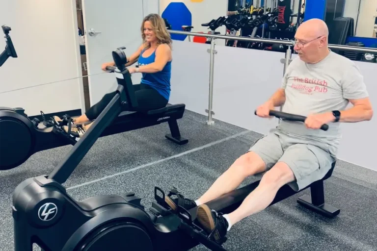 an older man and woman working out on rowing machines.