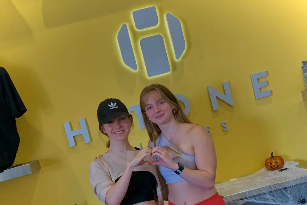 two women standing in front the Hitone logo.