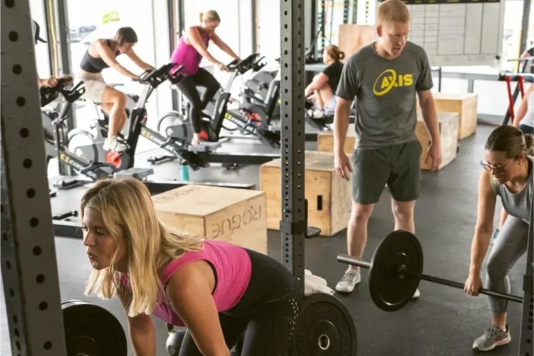 Personal trainer overseeing two women working out.