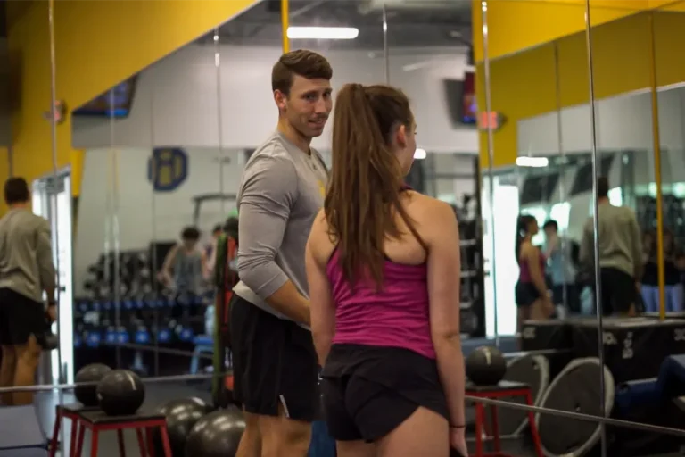 two people in a gym talking.