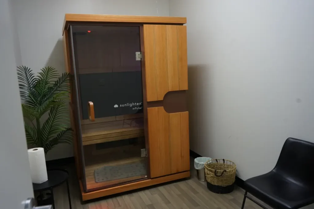 A mini sauna in a room with gray walls.