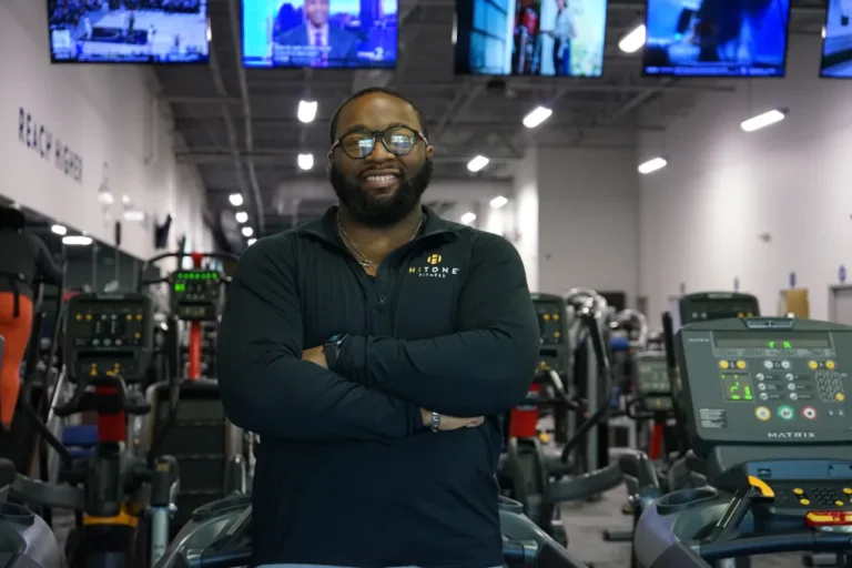 Man with glasses smiling while having his arms crossed.