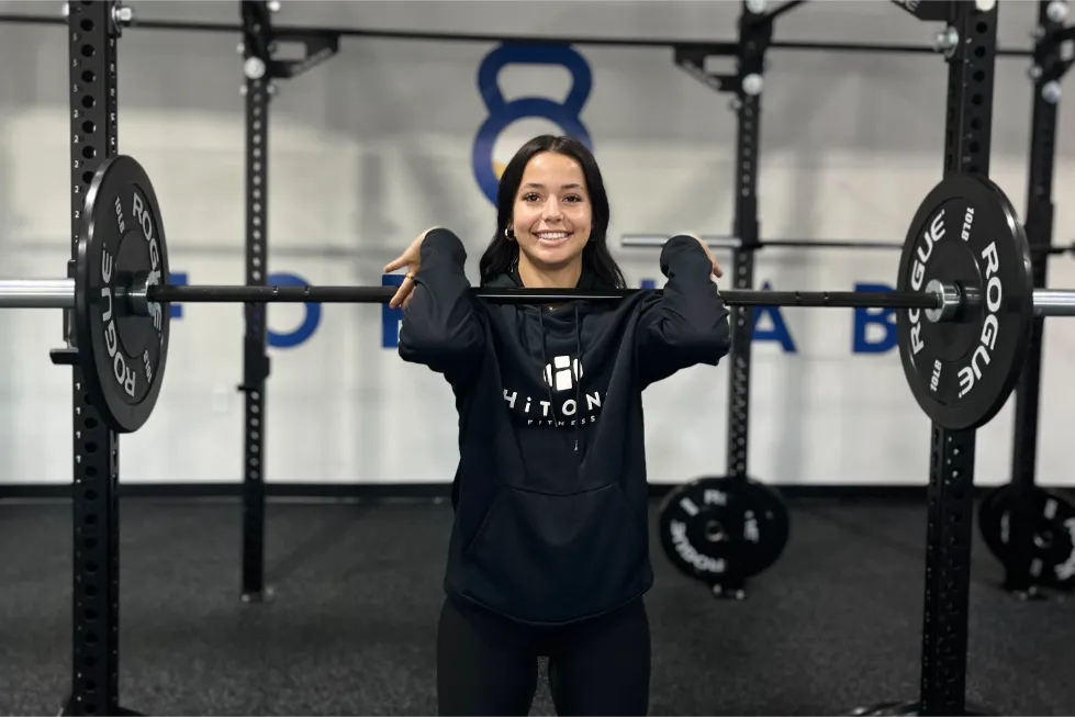 A smiling woman while preparing to lift weights.
