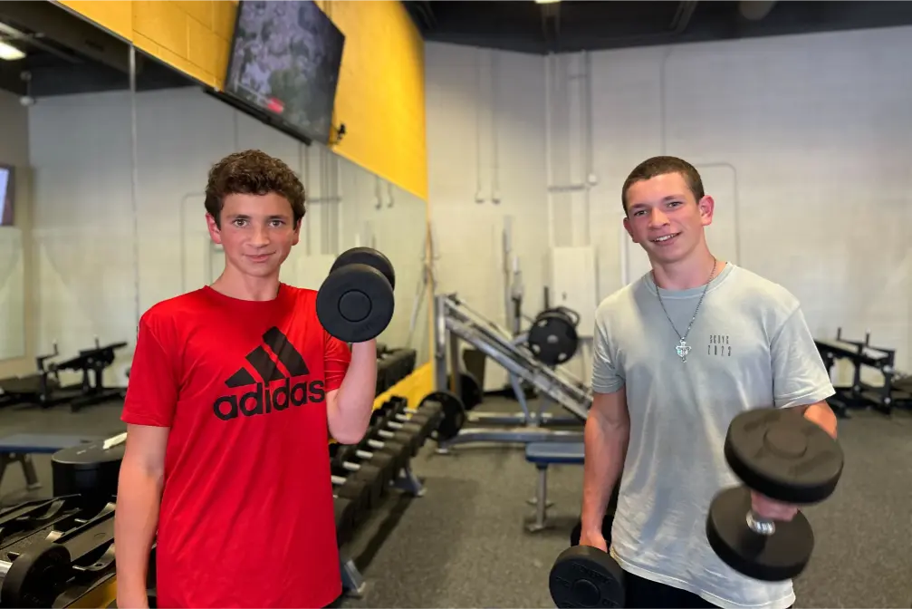 Two young men lifting dumbbells.