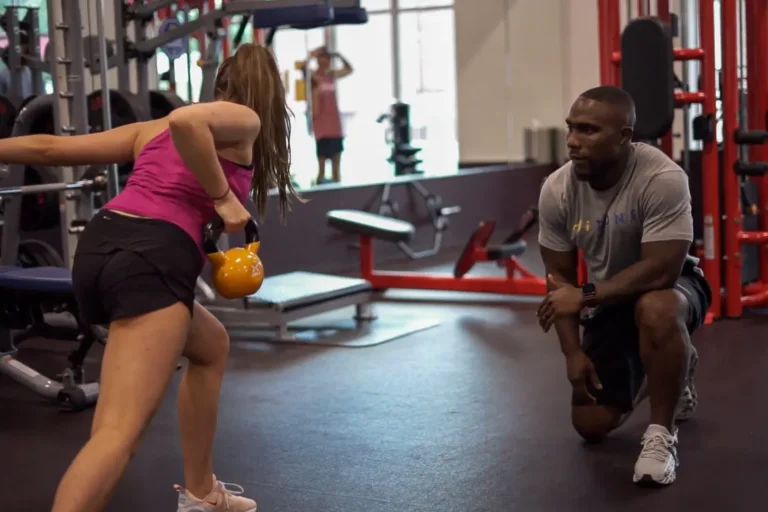 Trainer with his trainee, which is using a kettlebell.