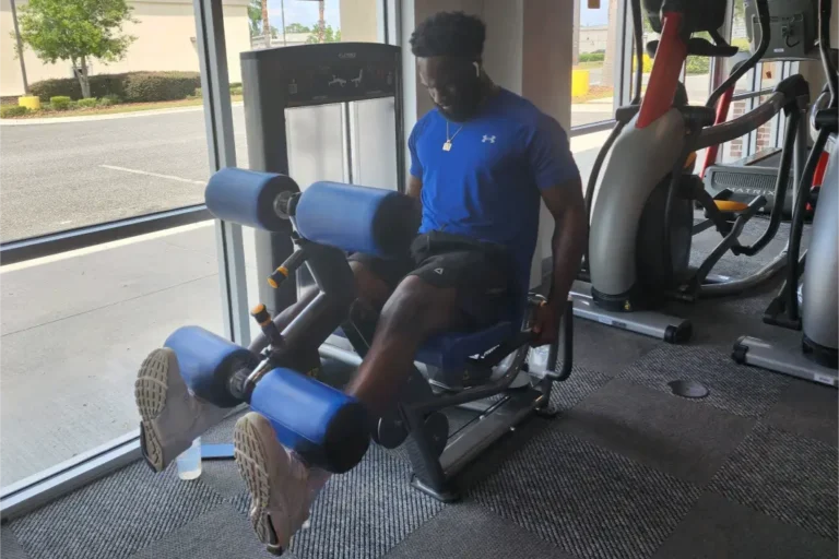 A person in a blue shirt working out his legs.