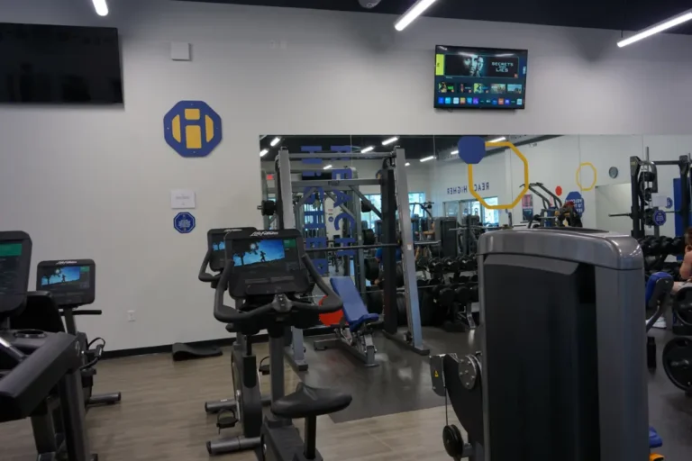 Inside of a gym with exercise bicycles and a power rack.