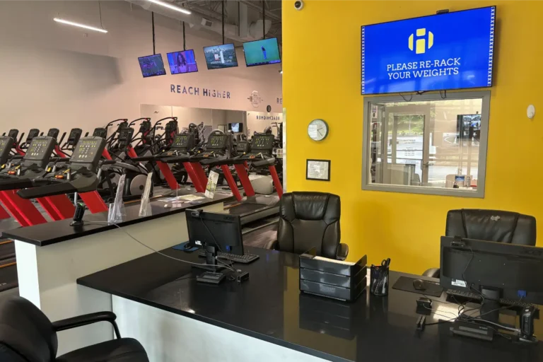 A desk with black chairs in a gym.