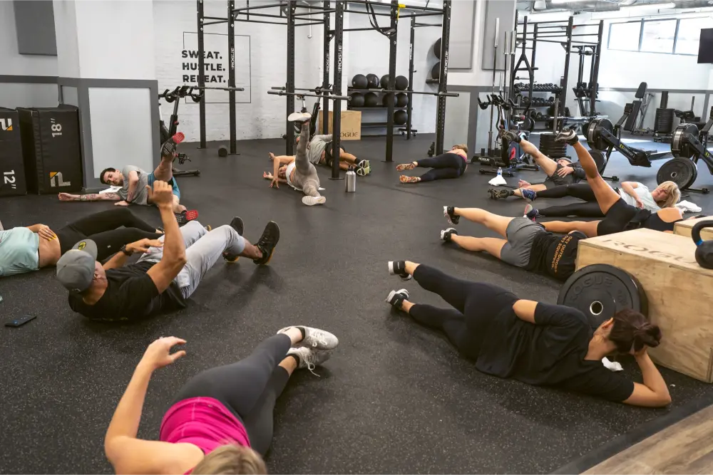 A group of people laying on the ground, doing a leg workout.