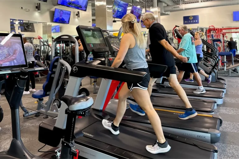 A woman, two older men, and an older woman doing cardio on treadmills.