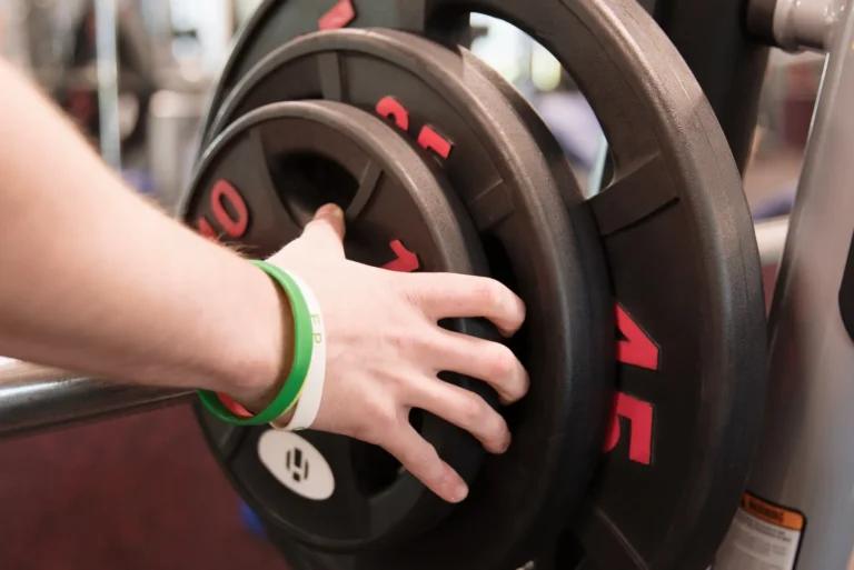 Someone placing plates on gym equipment.