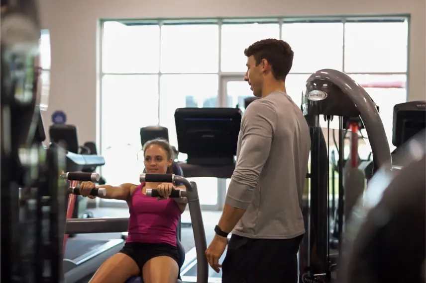 Man standing next to a woman working out.