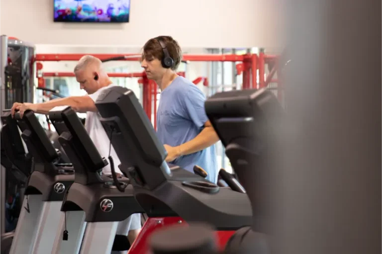 Two man on treadmills at a fitness center.