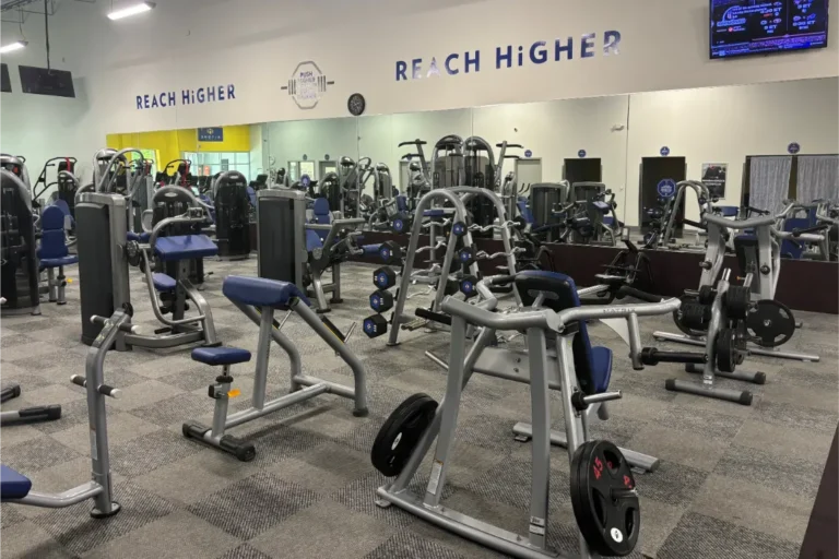 Various exercise machines and weight racks at a gym.