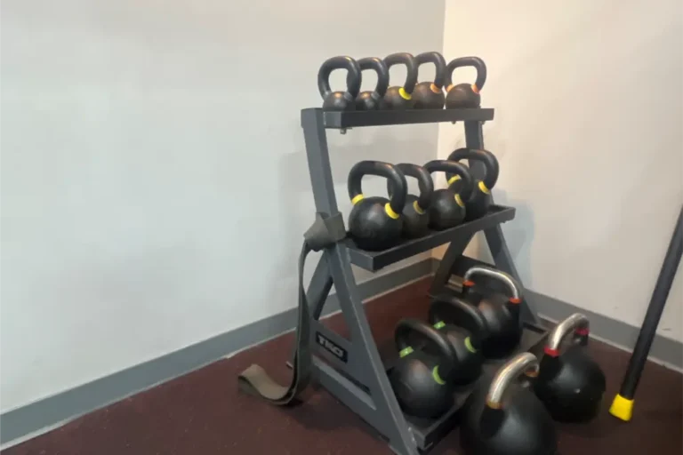 A rack holding twelve kettlebells. Two big kettlebells are placed beside it.