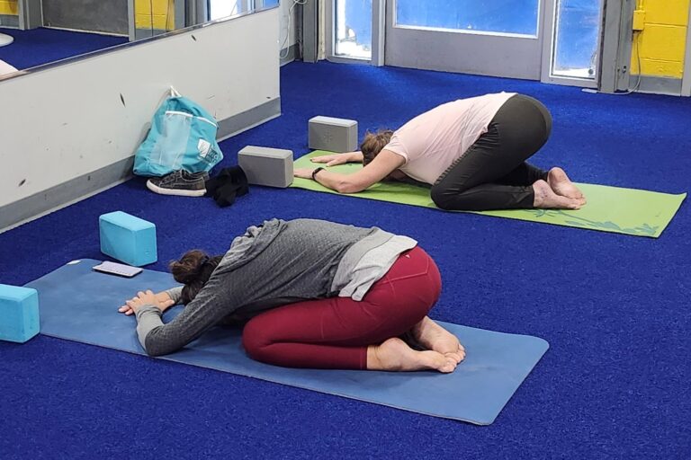 Two women doing child pose on their yoga mats.