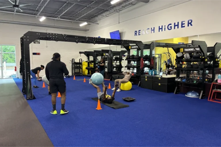 Two people doing ballance ball exercises next to at functional training rig.