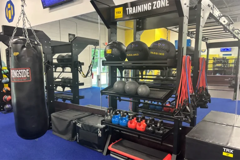 A boxing bag and a rack holding medicine balls and kettlebells.