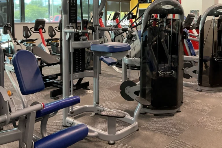 Vertical knee raise machine and other gym equipment at a fitness center.