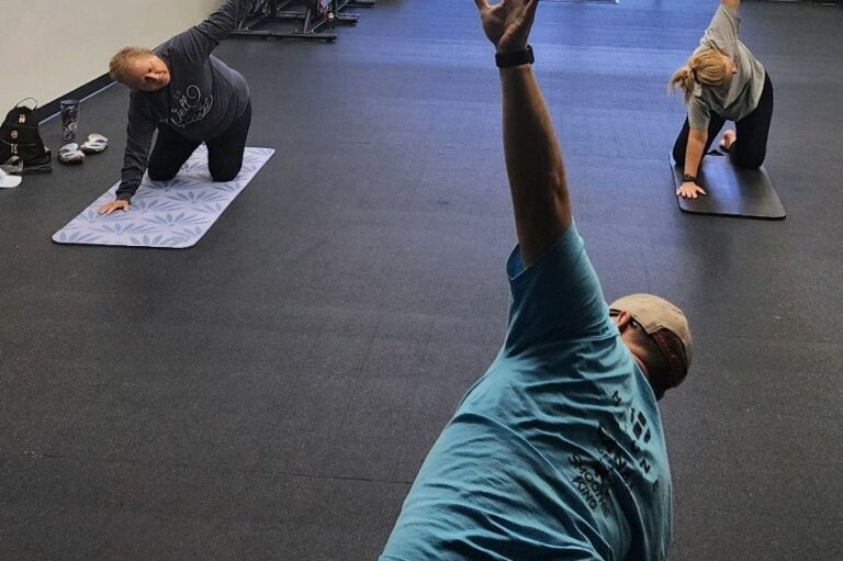 Three people doing the revolved triangle yoga pose.