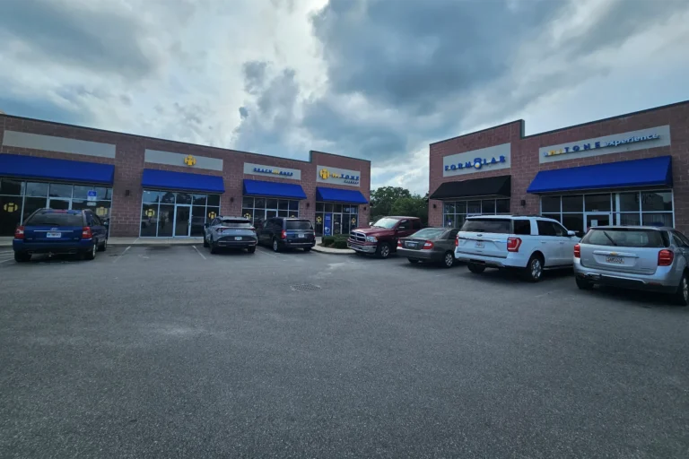 Parking with seven parked cars in front of a HiTONE fitness storefront.