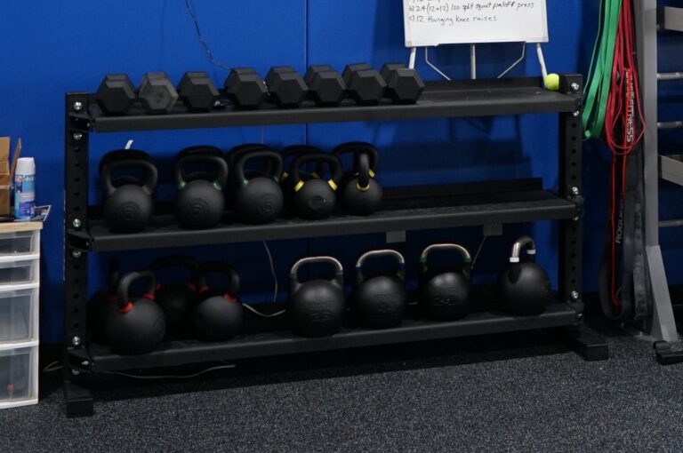 Hex dumbbells and kettlebells on a rack.