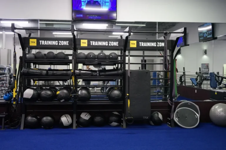 Medicine balls and other gym equipment on a rack inside a fitness center.