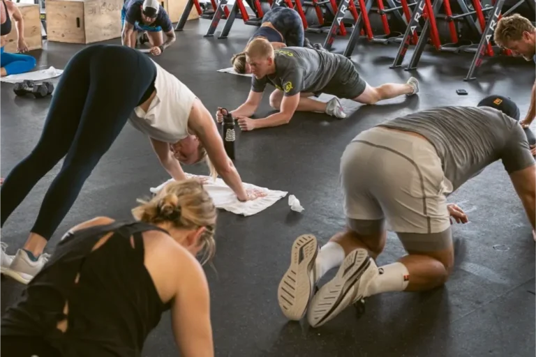 Eight people doing various yoga poses on the floor.