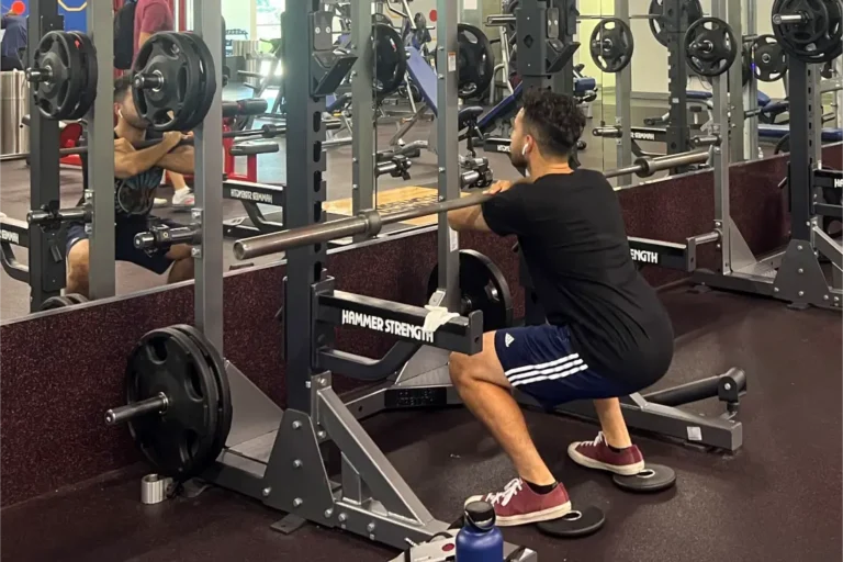 A man doing a front squat on a smith machine.