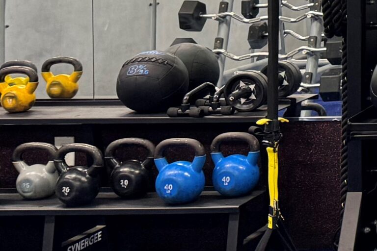 Kettlebells, medicine ball, push-up bars, and ab roller on a rack.