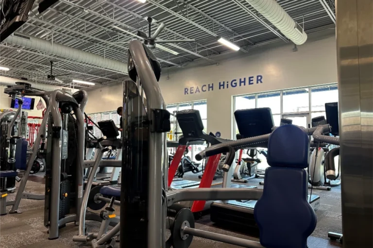 Inside of a gym with the "REACH HiGHER" lettering on the wall.