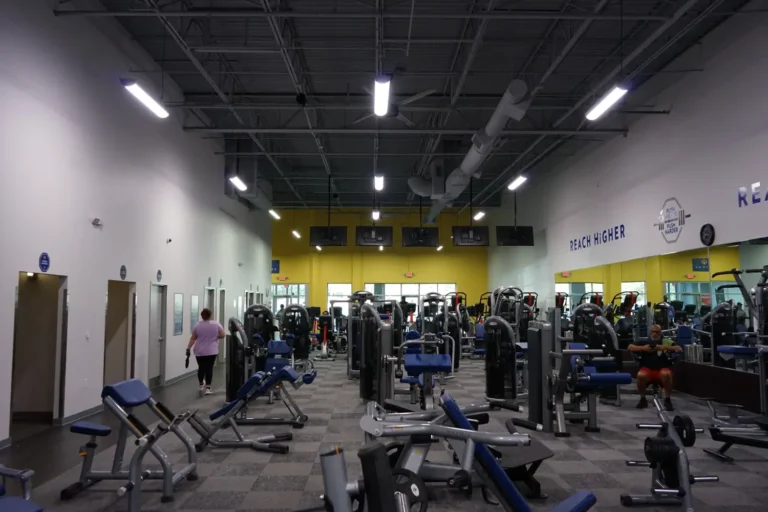 A room full of various gym equipment. "Reach higher" lettering on the white wall on the right.