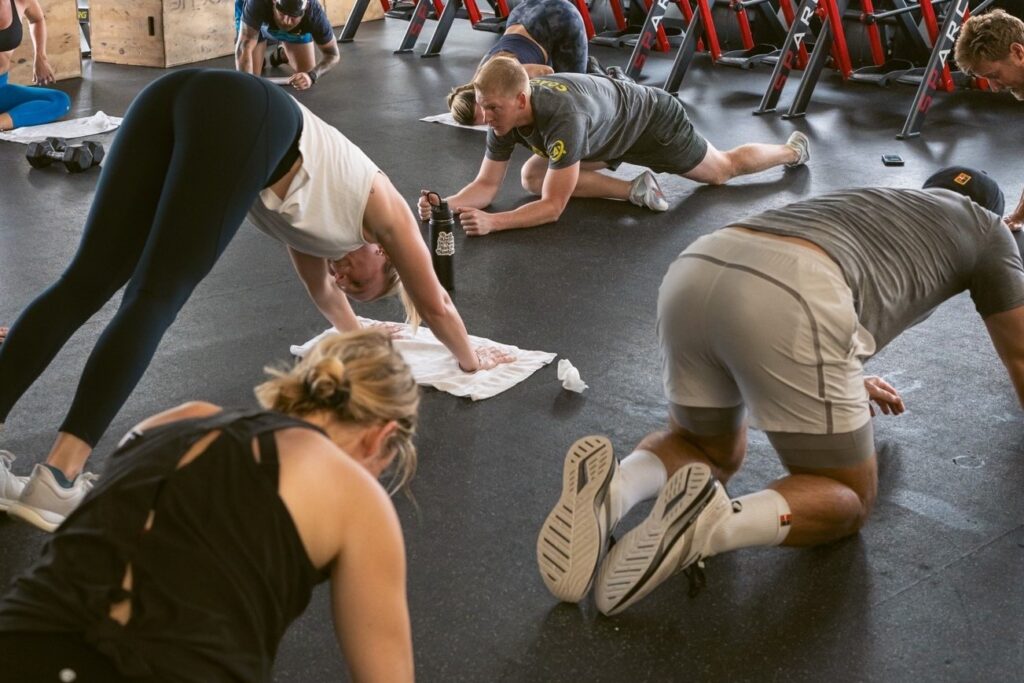 Eight people doing various yoga exercises on the floor.