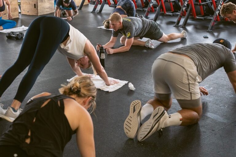 Eight people doing various yoga exercises on the floor.