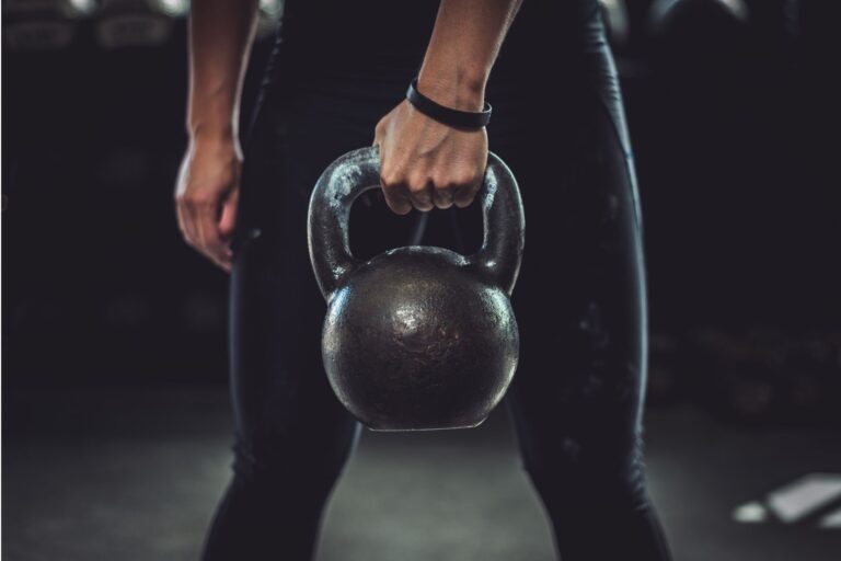 A person's hand holding up a kettlebell.