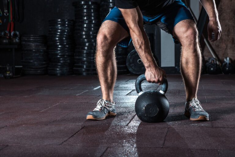 A man squatting and holding a kettlebell that's on the floor.