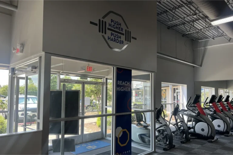 Enterance door of a gym with the "push harder" lettering on the wall above the door.