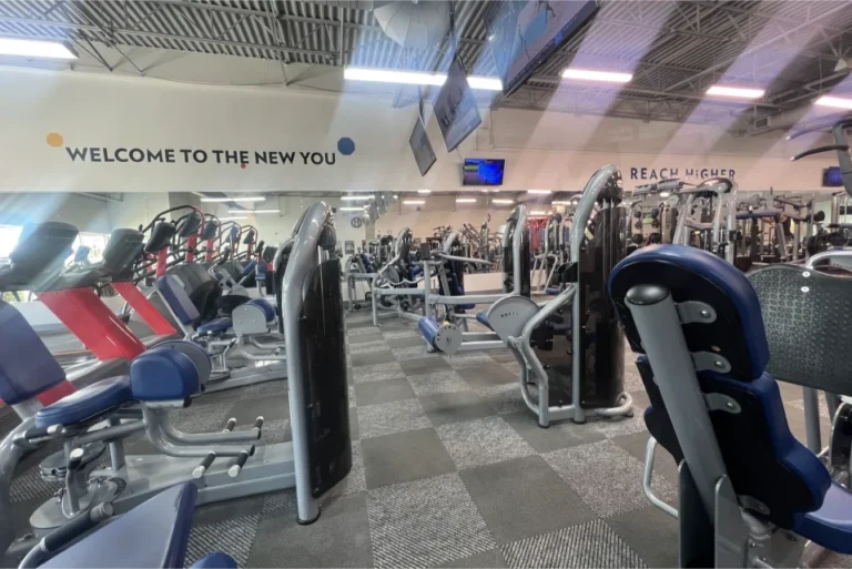 Inside of a gym with different machines and carpeted floor.