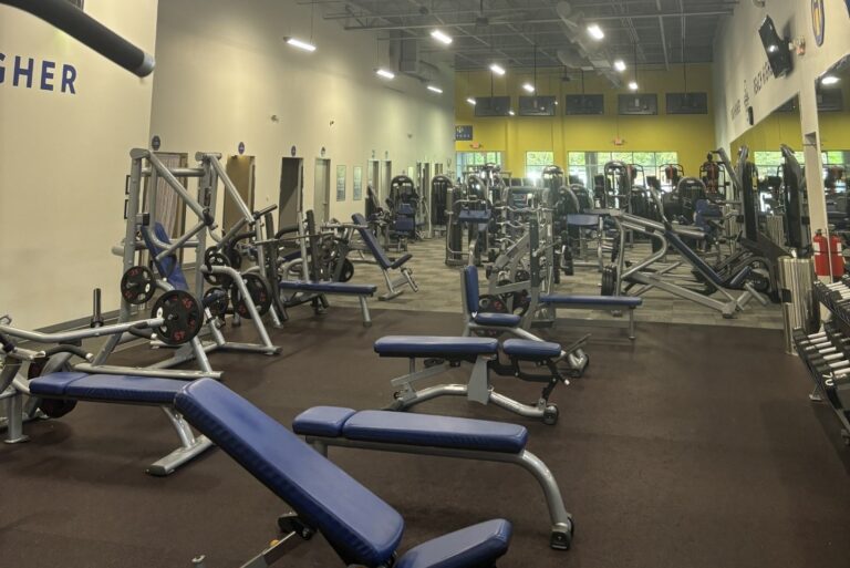 Inclined bench, flat benches, and other gym machines in a room.