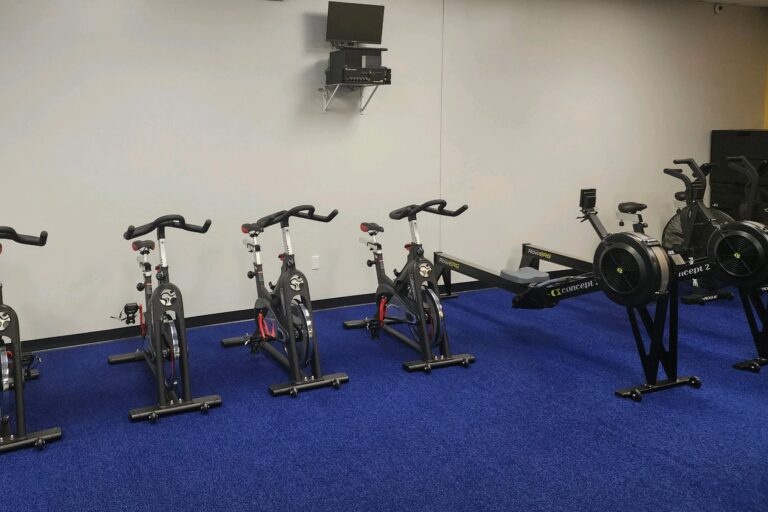 Exercise bicycles and rowing machines in a room.