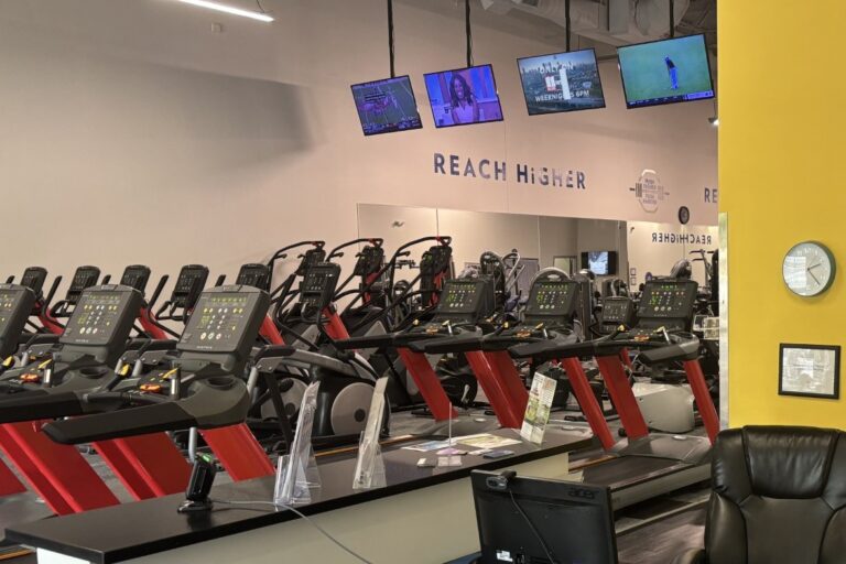 Various exercise equipment seen from a front desk at a gym.