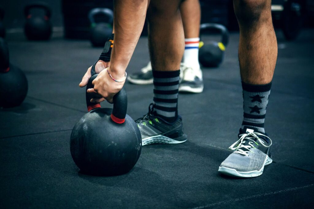 A man's hands are gripping the kettlebell on the floor.