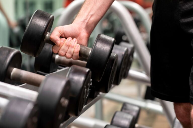 A man's hand picking up a dumbbell.