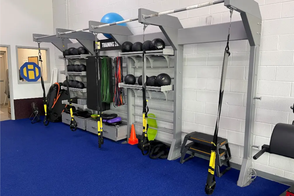 TRX suspension trainers, medicine balls, resistance bands, and balance equipment organized neatly on a racks.