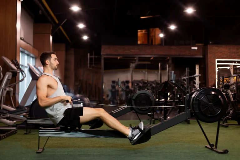 A man working out on a rowing machine outside in night time.