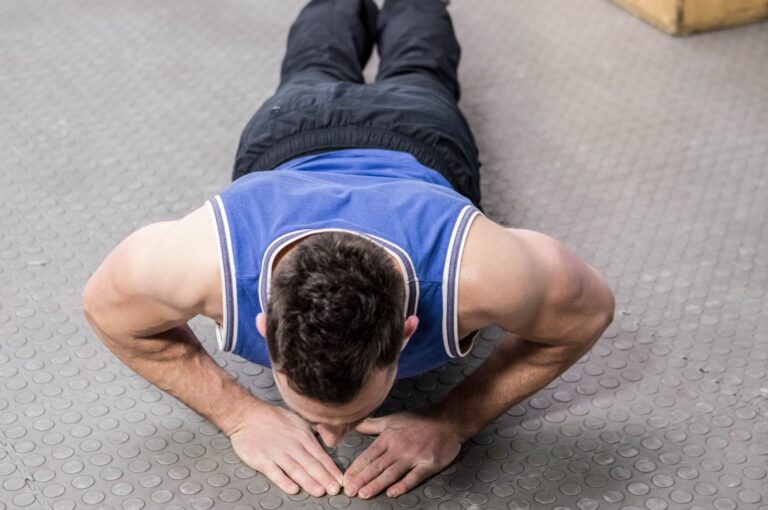 A man doing the diamond push-up exercise on a flat surface.