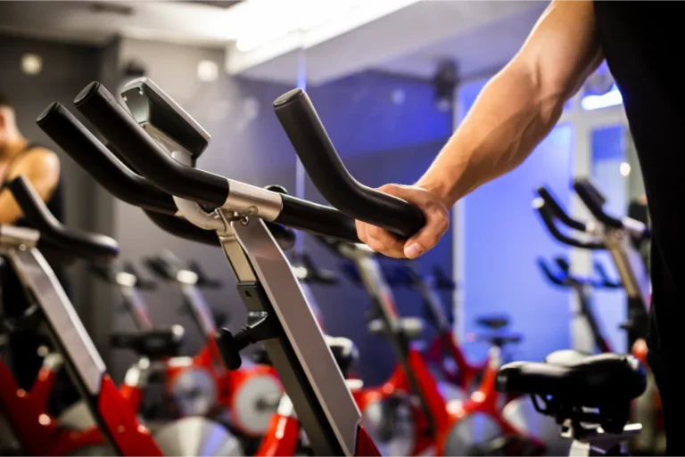 A man's hand gripping the handle of a stationary bike at a fitness center.